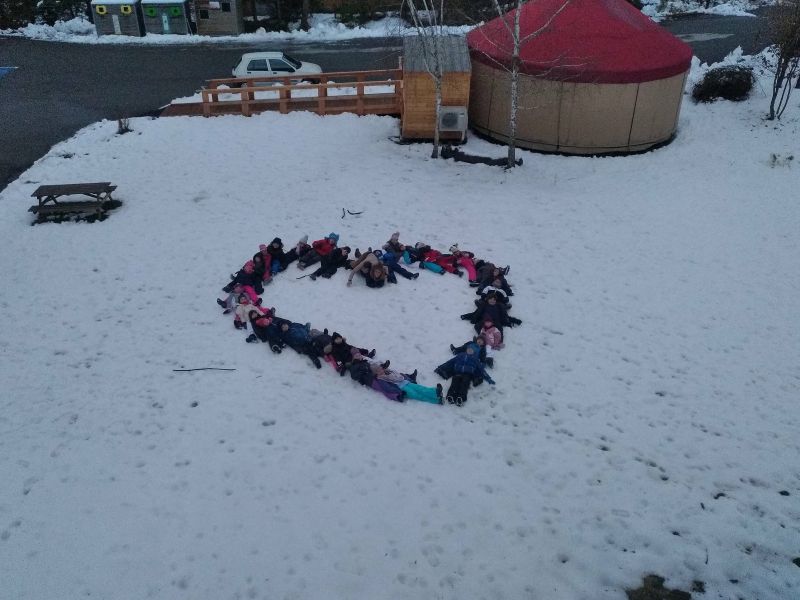 Coeur avec enfants couchés dans la neige devant la yourte