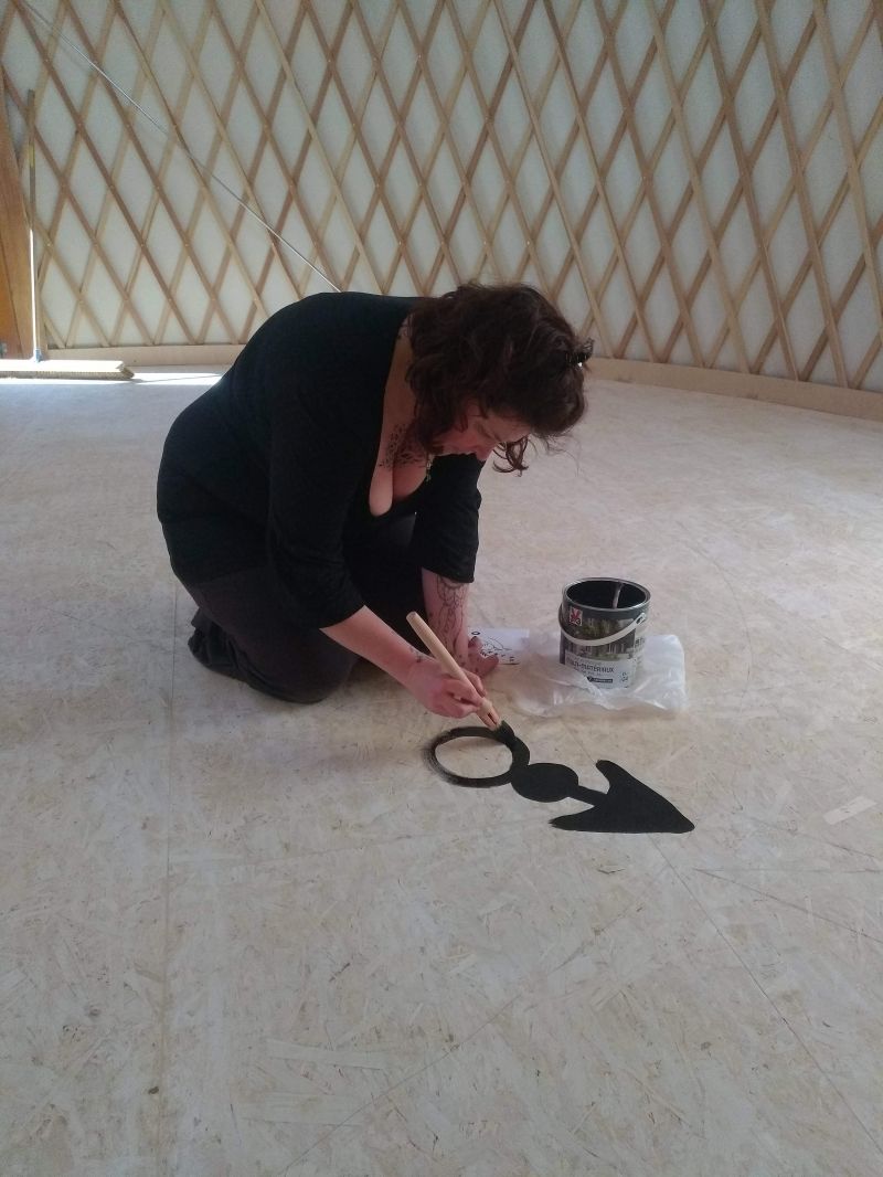 Aurélie-peint-la-rose-des-vents-sur-le-sol-de-la-yourte Aurélie-responsable-classes-de-découvertes--en-pleine-action-de-peinture-de-la-rose-des-vents-de-la-yourte-sensorielle